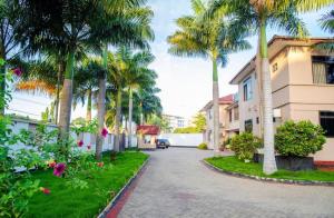 a street with palm trees and a building at Central Calm Apartment in Dar es Salaam