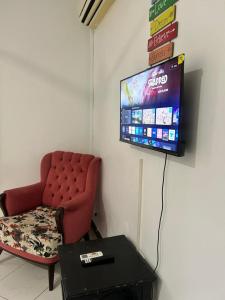 a living room with a red chair and a flat screen tv at Central Calm Apartment in Dar es Salaam