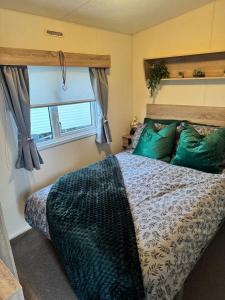 a bedroom with a bed with green pillows and a window at Haighs caravan hire in Rhyl