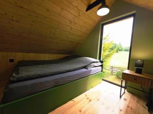 a bed in a room with a large window at Domek Daglezjowy in Małe Leżno