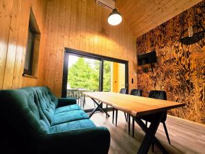 a dining room with a table and a green couch at Domek Daglezjowy in Małe Leżno