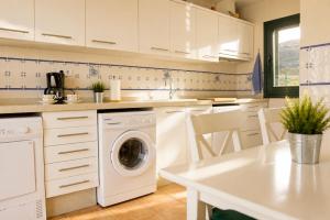 a white kitchen with a washing machine in it at La Cepada in Carrandi +15 photos