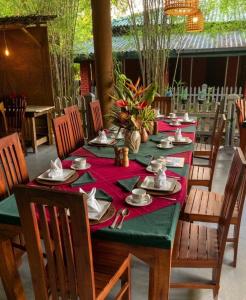 a long table with a red table cloth and chairs at Sunshine Resort & Spa Sigiriya in Sigiriya