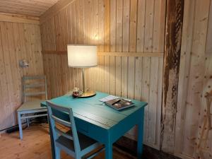 a blue table with a lamp and a chair at Kolin Mattila B&B in Kolinkylä