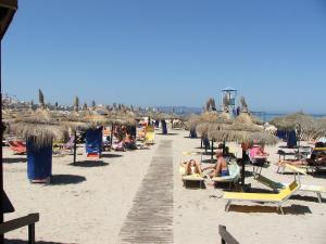 a beach with people sitting on chairs and umbrellas at B&B Il Sole Blu in Trapani