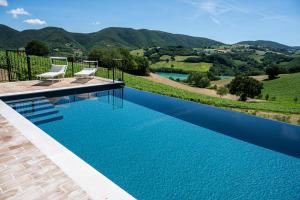 a pool with two chairs and a view of the mountains at La Corte Sul Lago in Cingoli