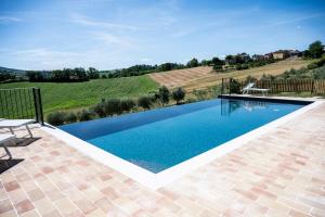 a swimming pool with a view of a vineyard and a house at La Corte Sul Lago in Cingoli +49 photos