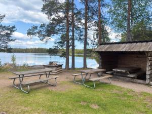 a picnic area with two benches and a building next to a lake at Hus Kråksmåla in Alsterbro