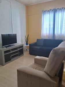 a living room with a blue couch and a tv at Ground floor apartment steps from the Cathedral in Santo Ângelo