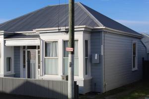 a white house with a black roof at Low Cost Accommodation in Dunedin