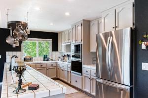 a kitchen with white cabinets and a stainless steel refrigerator at Copperopolis Home - Lake Access & Mtn Views in Copperopolis