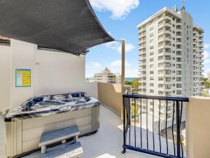 a balcony with a bed and a building at Nautilus Private Rooftop Spa in Mooloolaba