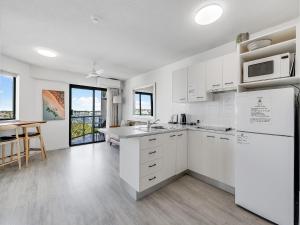 a kitchen with white appliances and a table and chairs at Nautilus Private Rooftop Spa in Mooloolaba
