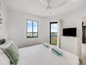 a white bedroom with a white bed and a tv at Nautilus Private Rooftop Spa in Mooloolaba