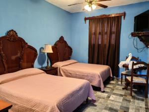 a hotel room with two beds and a tv at Hotel Tlacotalpan in Tlacotalpan