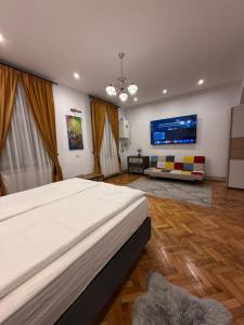 a bedroom with a bed and a couch and a tv at Insieme Studio - Small Square in Sibiu