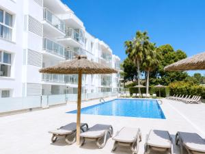 a swimming pool with chairs and umbrellas next to a building at Rentalmar Pins Marina in Cambrils