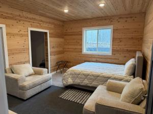 a bedroom with a bed and two chairs and a window at Cedar Studios at Whitetail Estates in Babbitt