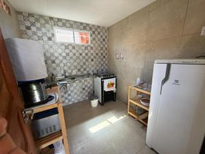 a small kitchen with a refrigerator and a stove at Brisa da Mata Suítes BF quarto 02 in Baía Formosa