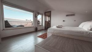 a bedroom with a bed and a large window at NURAS - Casa degli Anemoni in Porto Conte
