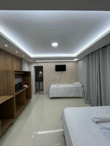 a bedroom with two beds and a tv on the wall at Maxi Palace hotel in Capitão Leônidas Marques