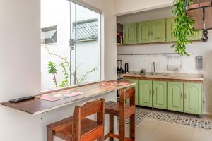 a kitchen with green cabinets and a table and chairs at Casa e Suíte Brisa do Bosque in Belém