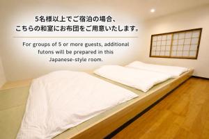 a bed in a room with the words for groups of or more guests at iORi Yufuin ーVacation House With Private Hot Spring in Yufu
