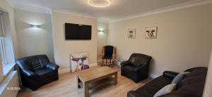 a living room with a couch and chairs and a tv at Rosmore Newport in Newport