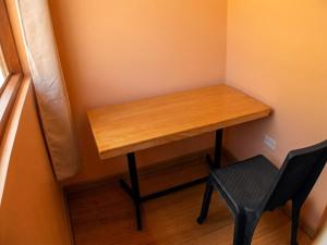 a wooden table in a corner with a black chair at Imasmari Wasi in Pisac