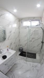 a white bathroom with a shower and a sink at Appartement Aokas Béjaïa in Aokas
