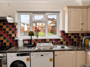 a kitchen with a sink and a washing machine at 3-Bedroom House ,Quiet & Spacious in Kent