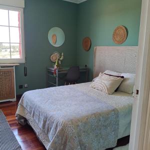 a bedroom with a bed with green walls and a window at Casa Dulce in Villaviciosa