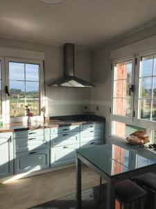 a kitchen with white cabinets and a glass table at Casa Dulce in Villaviciosa +28 photos