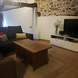 a living room with a couch and a tv at Casita del Castillo Mora de Rubielos in Mora de Rubielos