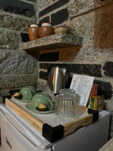 a counter with a tea set on top of a refrigerator at Chalé Carrara, um Refúgio de Pedra na Mata - Chalés Flor dos Manacás in Santa Teresa