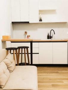 a kitchen with white cabinets and a couch and a counter at Charma Urban Living in Bendevís +8 photos