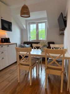 a kitchen and living room with a table and chairs at Apartament Lubię Błękit in Rowy