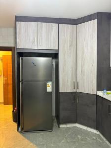 a stainless steel refrigerator in a kitchen with wooden cabinets at 3 BR apartment, fully renovated in Amman