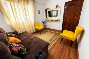 a living room with a brown couch and yellow chairs at Casa p/ 7 | 3 quartos c/ ar e churrasqueira in Ourinhos