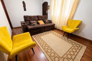 a living room with a couch and two yellow chairs at Casa p/ 7 | 3 quartos c/ ar e churrasqueira in Ourinhos