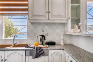 a kitchen with white cabinets and a sink and a window at Pallas in Keratea
