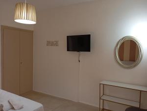 a room with a tv on a wall with a mirror at Nadia Studios in Kalamaki