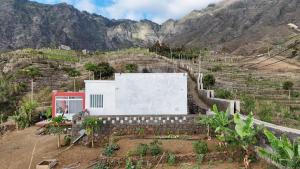 a building on a hill with mountains in the background at Casa Terra Odjo N'mar in Janela