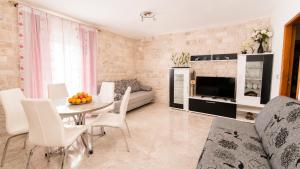 a living room with a table and white chairs at Apartment Romić in Omiš