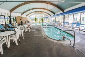 a swimming pool with tables and chairs in a building at Holly Tree Resort - Studio in Yarmouth