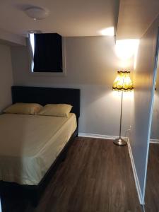 a bedroom with a bed and a lamp on the floor at Beautiful home in Brampton