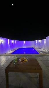 a table in front of a swimming pool at night at Oasisi 360 in Sowayma