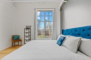 a bedroom with a bed with a blue headboard and a window at Rooftop Pool & City Views! Long-Term Dtwn LA Stay in Los Angeles +26 photos