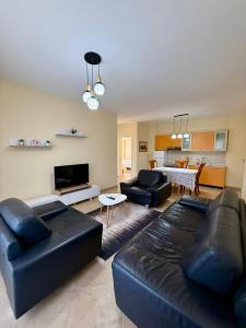 a living room with black leather furniture and a kitchen at Vlora Center Apartment - 5 Min to Lungomare in Vlorë