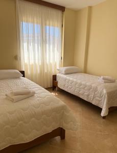 two beds sitting in a room with a window at Vlora Center Apartment - 5 Min to Lungomare in Vlorë